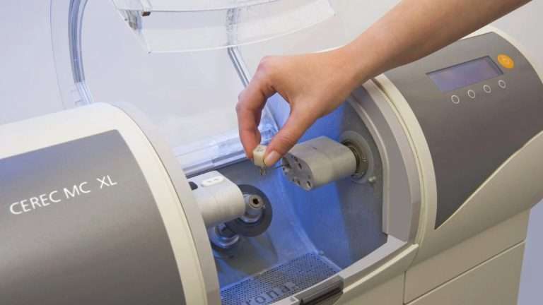 Hand placing a ceramic block into the CEREC MC XL dental milling machine