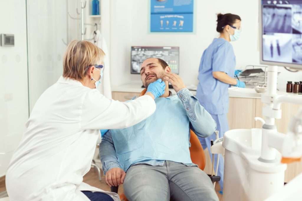 Dentist examining patient with severe pain due to wisdom tooth pain during an emergency dental visit.