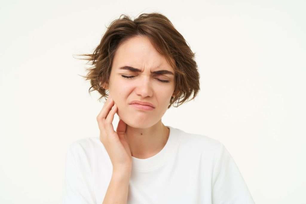Woman holding her cheek in pain, illustrating the need for TMD treatment (Night Guards vs BOTOX®). Mississauga Smiles Dentistry, Mississauga.