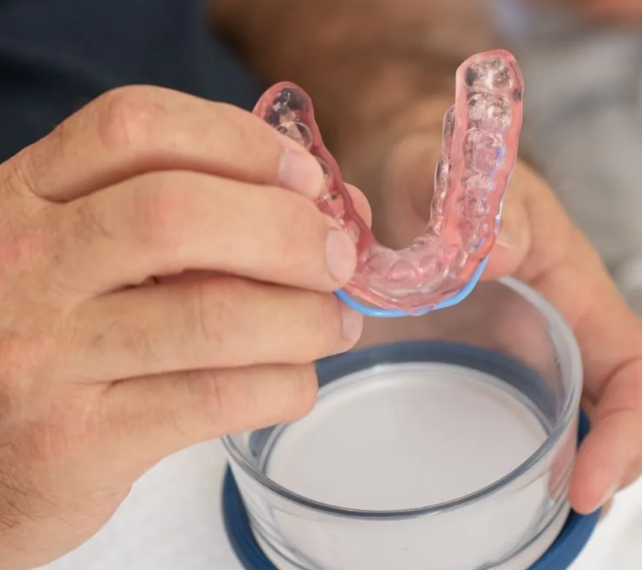 SomnoMed oral appliance held by a person, shown in its case, for sleep apnea treatment.
