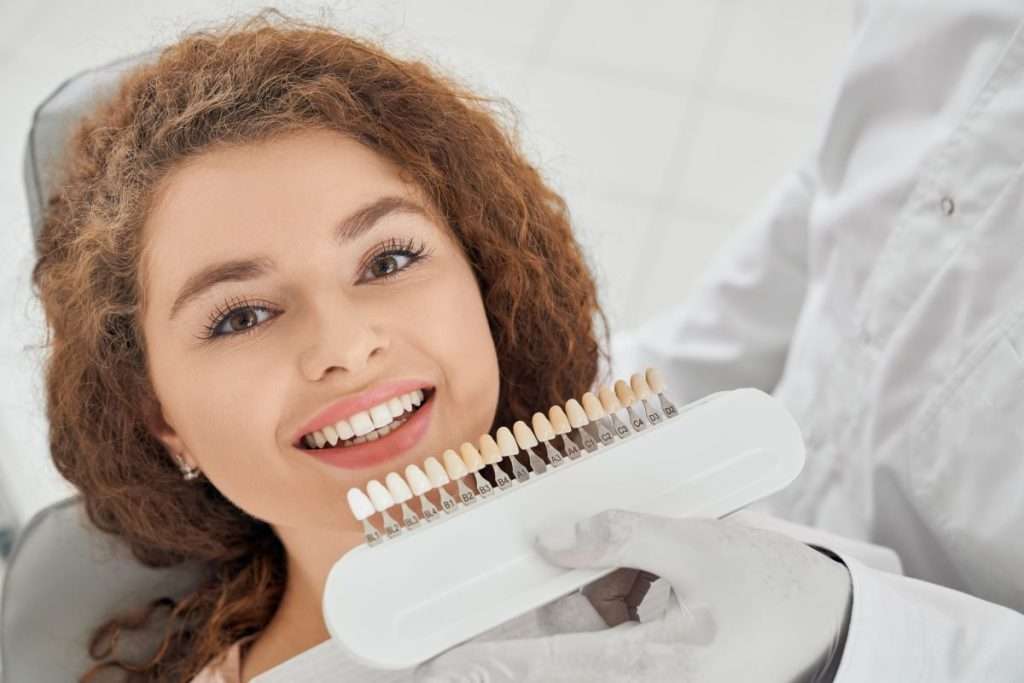 Young woman smiling with a dentist and matching veneer shades for a Smile Makeover procedure