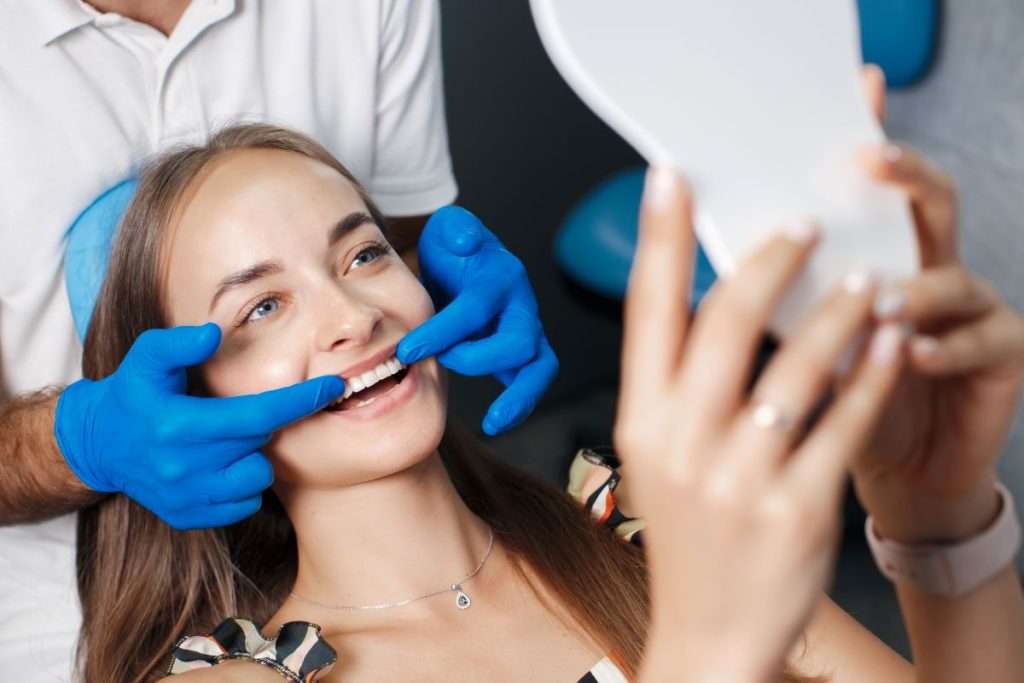 Dentist showing patient her bright, natural smile after Porcelain and Composite Veneers treatment.