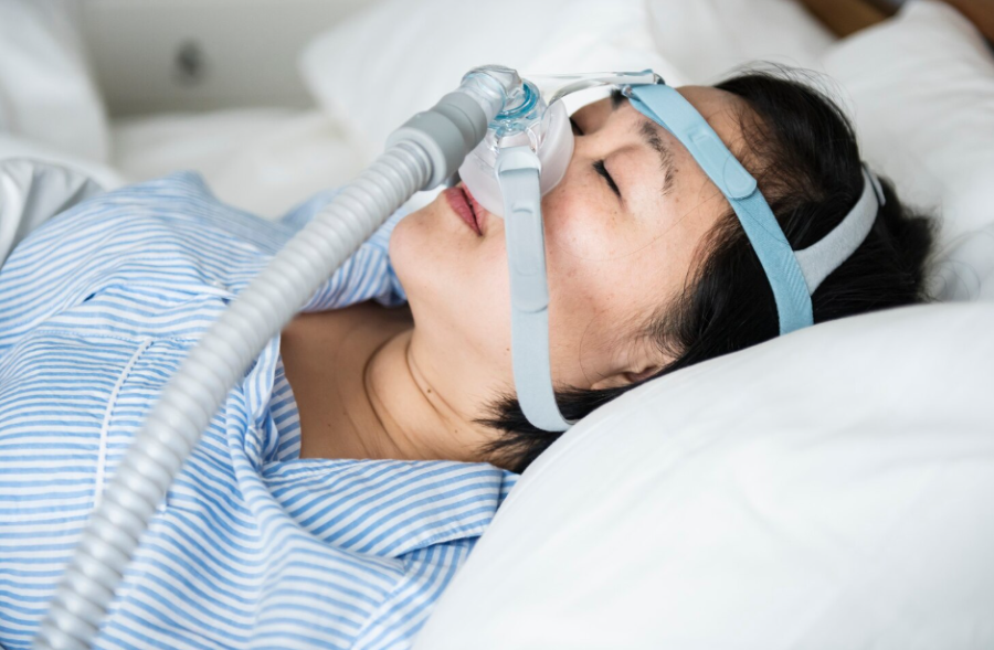 Woman sleeping with CPAP device for sleep apnea therapy.