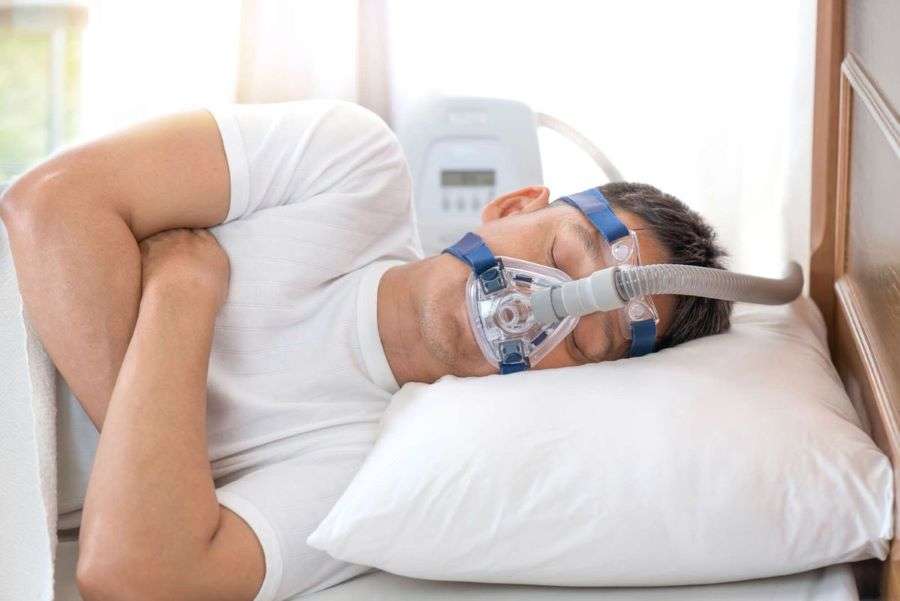 Patient sleeping with CPAP device to treat sleep apnea